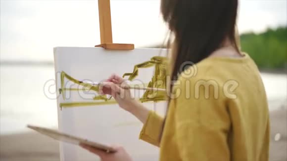 年轻女子画家在画架上画水彩画视频的预览图
