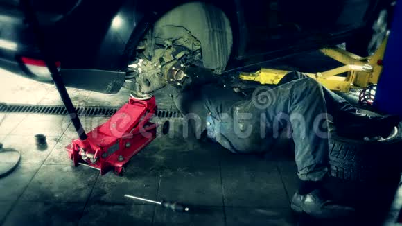男技术员躺在修车厂的车底下工作视频的预览图