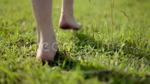 快乐的女孩赤脚跑在绿草上视频的预览图
