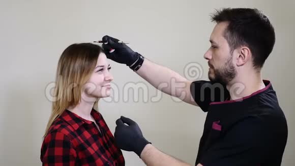 美容院男性美容师戴着黑色手套在永久化妆程序之前涂上眉毛眼线青年视频的预览图