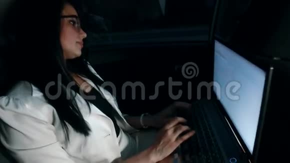 出租车上的女人晚上在车里的笔记本电脑上工作视频的预览图
