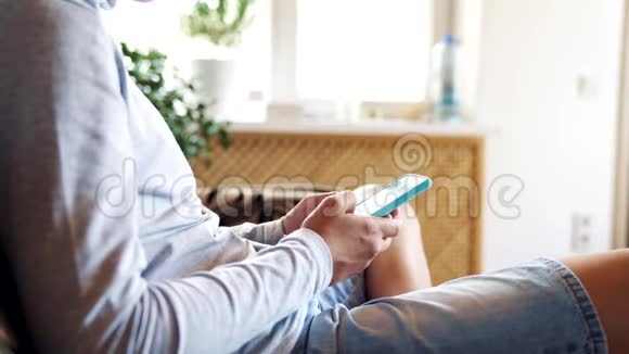 男孩坐在房间里的沙发上用智能手机现代技术在儿童生活中的概念视频的预览图