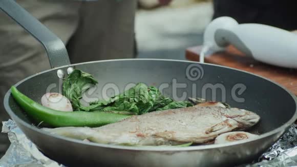 在装有胡萝卜切叶和洋葱的平底锅中煎烤奥赫里德湖褐鳟视频的预览图