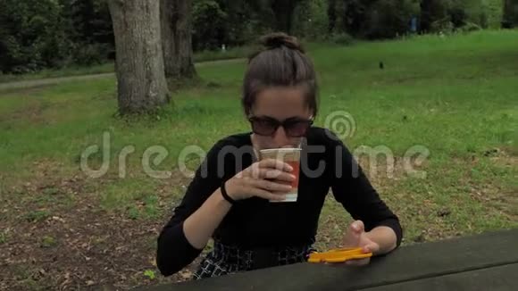 4K漂亮的女孩穿着手工制作的长袖衬衫戴着绿棕色太阳镜坐在木制的乡村餐桌旁视频的预览图