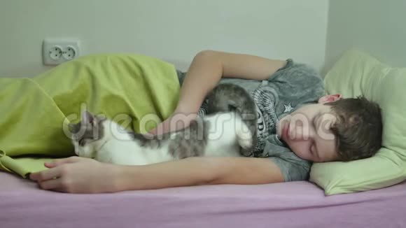 十几岁的男孩睡在床上男人累了毛茸茸的十几岁的室内男孩睡觉宠物猫视频的预览图