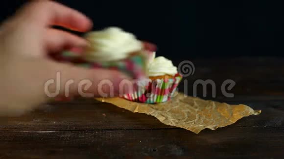 在烤纸上涂上蛋糕霜的松饼把手放在桌上视频的预览图
