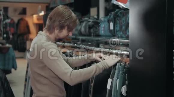 购物男人在商场的衣架上选择牛仔裤极致店顾问检查裤子视频的预览图