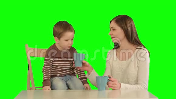 儿子和母亲在绿屏上喝茶视频的预览图