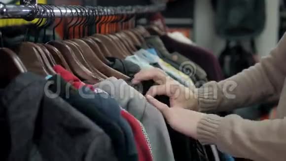 在一家零售服装店男士毛衣和不同颜色的衬衫挂在衣架上男士则选择店里贴身的帽衫视频的预览图