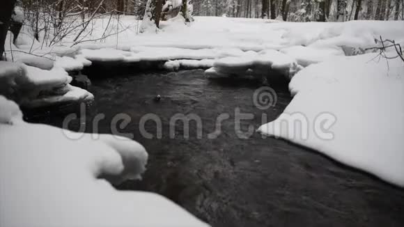 森林中带河的雪冬景观流动的水和破冰视频的预览图