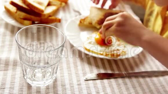 一个孩子正在吃早餐炒鸡蛋烤面包和沙拉而一个家长则把橙汁倒进他的杯子里视频的预览图
