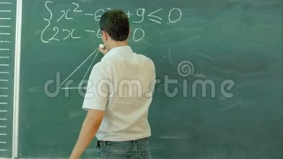 年轻的男教师或学生拿着粉笔在教室的黑板上书写视频的预览图