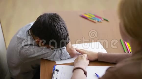 男孩在与年轻的心理学家交谈时沉默地坐着握着手视频的预览图