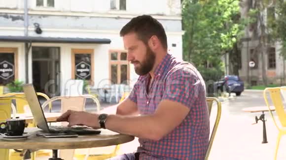年轻人在咖啡馆里的笔记本电脑上写字滑杆左射视频的预览图