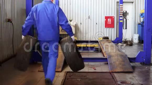 男性机械师携带磨损的轮胎存放冬季用过的轮胎视频的预览图
