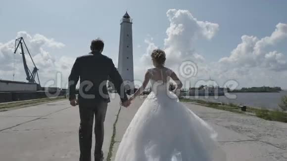 一对年轻夫妇牵着手去灯塔浪漫的爱俄罗斯新婚快乐的年轻夫妇享受视频的预览图