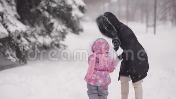 父母和孩子在雪地里玩耍妈妈和女儿在冬天的树林里雕刻雪视频的预览图
