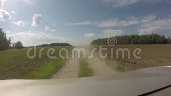 汽车后面的灰尘在田野里的乡间小路上从车上看到后景视频的预览图