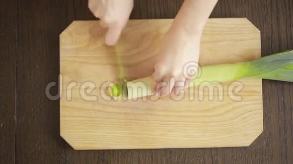 女人手拿刀在厨房的木板上割韭菜视频的预览图