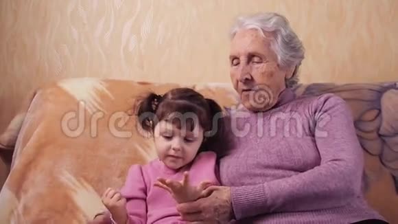 奶奶和孙女玩奶奶和孙女在家里的沙发上玩得很开心视频的预览图