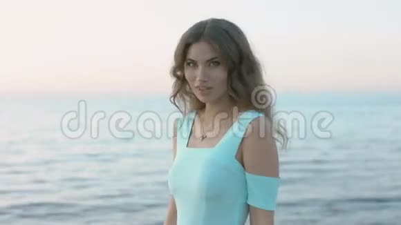 漂亮的模特穿着一件蓝色的裙子摆在海边视频的预览图