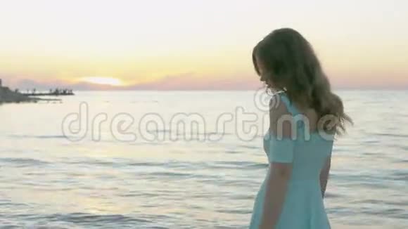 漂亮的模特穿着一件蓝色的裙子摆在海边视频的预览图