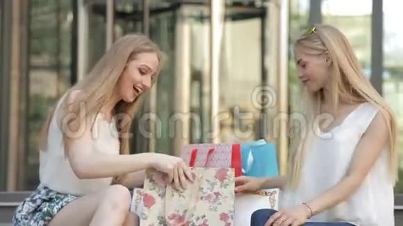 女孩们拿着购物袋坐在台阶上大买大卖后视频的预览图