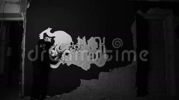 艺术家在黑色的墙上画有头骨的白色格雷菲蒂视频的预览图