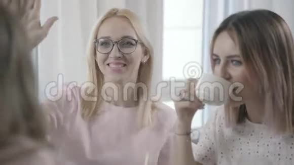 两个年轻的女人坐在咖啡馆里和她们的朋友交流视频的预览图
