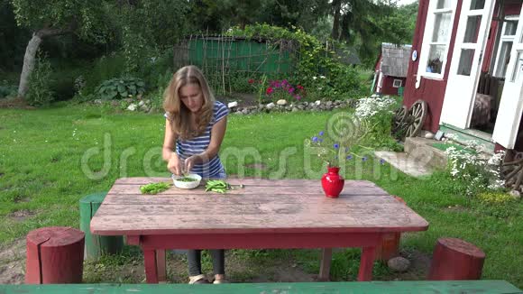 村民金发女孩在农村房子附近的木桌上豆荚绿豌豆4K视频的预览图