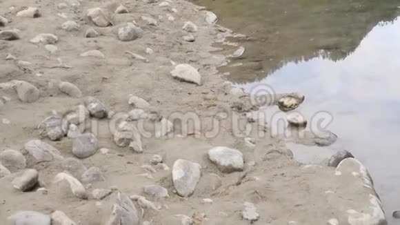 沿着一个小湖岸的圆形石头和沙子视频的预览图