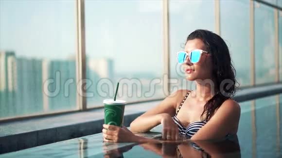 亚洲微笑的女人在游泳池里喝鸡尾酒视频的预览图