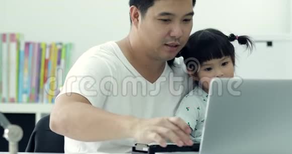 亚洲现代家庭和小女孩而爸爸则用笔记本工作视频的预览图