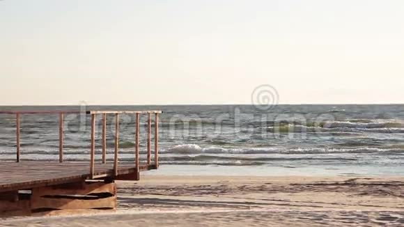 在一个多风的日子里当海浪来到海滩上建造的木制甲板时可以看到海岸的景色视频的预览图
