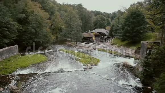 从山顶俯瞰一条美丽的山河俯瞰一座可爱的木制建筑创造了惊人的瀑布视频的预览图