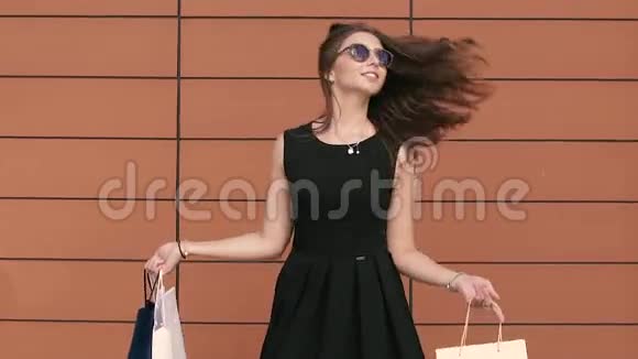 一个年轻的女人带着购物袋挥舞着她美丽的头发视频的预览图