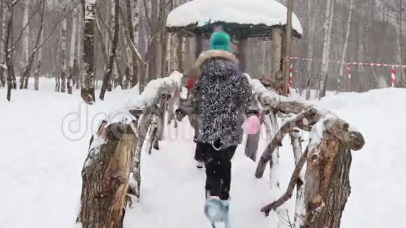 冬天公园下雪时快乐的小男孩和小女孩在桥上奔跑视频的预览图