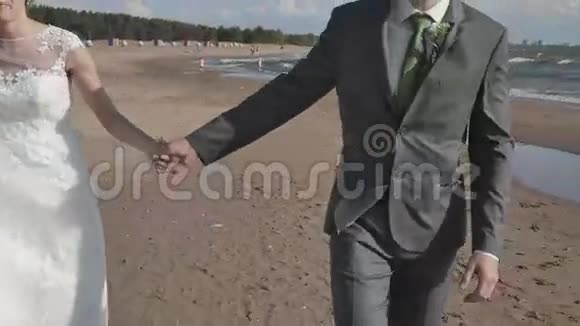 新婚夫妇牵着手走在海滩上镜头移动视频的预览图