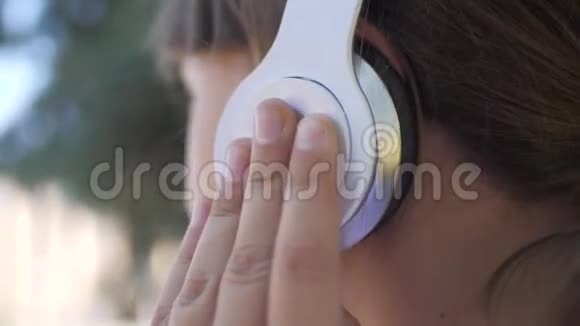 夏天在公园里听音乐跳舞戴耳机的快乐少女视频的预览图