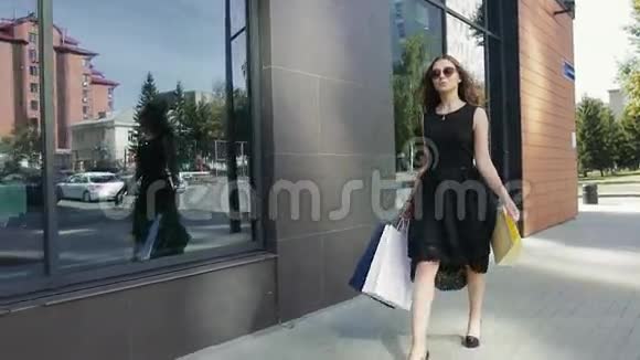 美丽的年轻女子在购物后快乐地散步视频的预览图