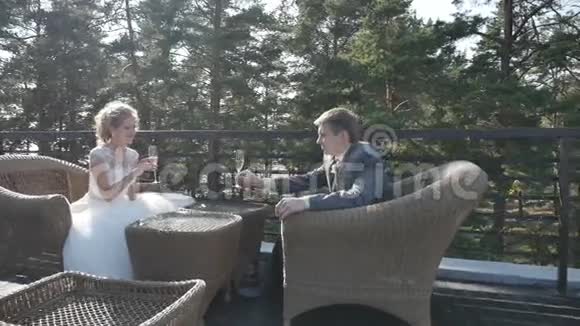 新娘和新郎坐在阳台上喝香槟夏天的咖啡馆Stadicam视频的预览图