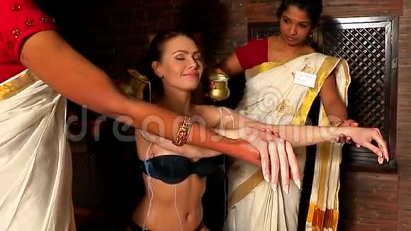 有阿育吠陀温泉治疗的女人两个真正的印度按摩师正在给病人倒油视频的预览图