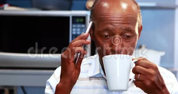 在厨房喝咖啡的时候老人在用手机说话视频的预览图