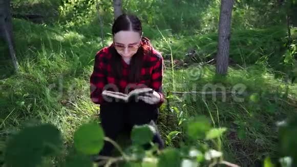 女人在绿色的夏日森林里看书视频的预览图