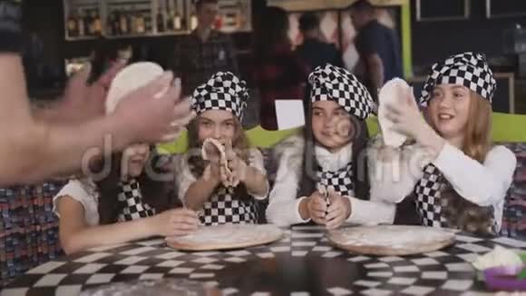 四个穿着制服的快乐女孩在主班做披萨视频的预览图