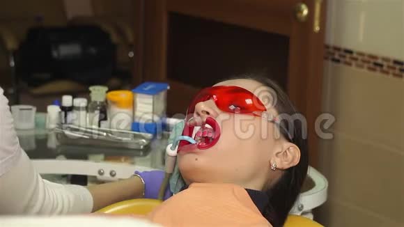 在牙科诊所有扩张器的年轻女子保护美白凝胶在牙齿上的应用视频的预览图