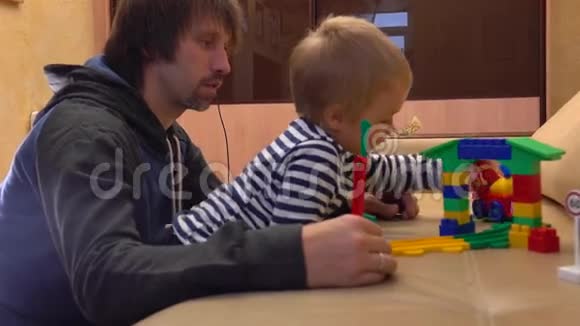 爸爸和他的小儿子一起玩五颜六色的建筑他的父母和他的孩子有空闲时间视频的预览图