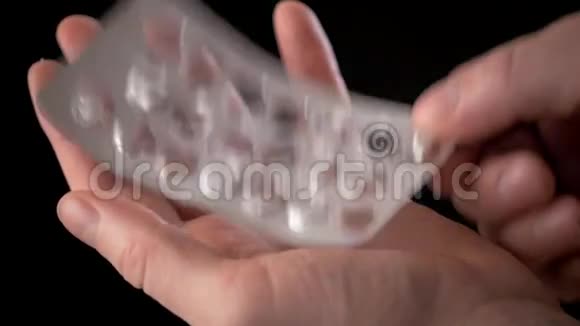 病人的手拿着一组用过的药片覆盖在黑色上药物过量药物滥用的概念上视频的预览图