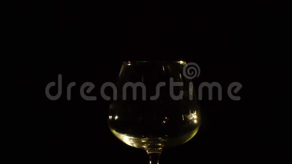 在杯中的黑色背景上倒入白兰地视频的预览图