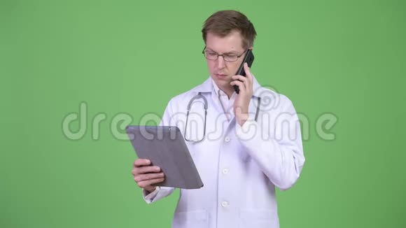 男子医生使用数码平板电脑同时使用手机视频的预览图